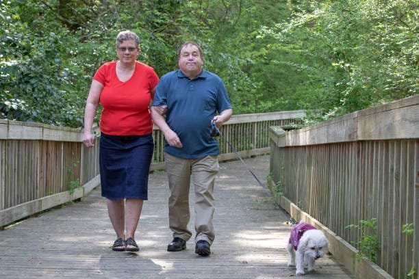 Autistic man and his caretaker walking a dog
